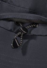 Gros plan sur un cordon noir avec un verrouillage en plastique sur un tissu gris foncé, montrant les coutures et les détails texturés.