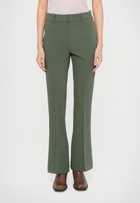 Pantaloni verzi tailandați cu picior evazat, cu un front plat, bucle pentru curea și o textură netedă. Asortați cu cizme din piele maro.