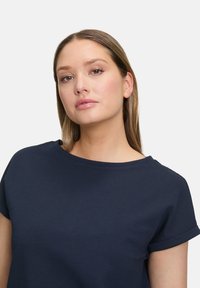 Mørkeblå t-shirt med rund halsudskæring og rullede korte ærmer. Lavet af struktureret stof med en afslappet pasform.