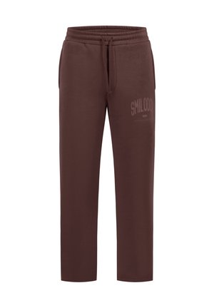 Brązowe spodnie dresowe o prostych nogawkach z elastycznym pasem i sznurkiem, przednimi kieszeniami oraz delikatnym napisem "SMILODO" na górnej części uda.