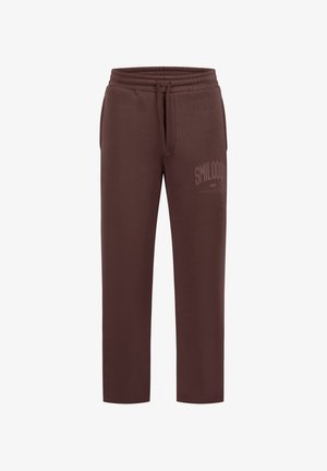 Brązowe spodnie dresowe o prostych nogawkach z elastycznym pasem i sznurkiem, przednimi kieszeniami oraz delikatnym napisem "SMILODO" na górnej części uda.
