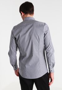 Grau karierter Hemd mit langen Ärmeln, Knopfärmelbündchen und Kentkragen. Verfügt über eine glatte Textur und eine taillierte Passform.