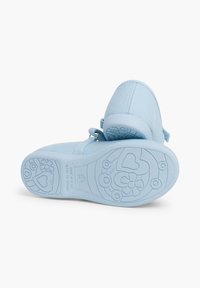 Zapatillas infantiles de color azul claro con parte superior de tejido suave, correa ajustable y suela de goma texturizada con patrones de corazones y flores.