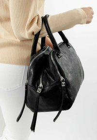 Schwarze Leder-Handtasche mit strukturierter Oberfläche, zwei oberen Reißverschlüssen und zwei kurzen Griffen, ausgestattet mit silbernen Beschlägen und hängenden Akzenten.