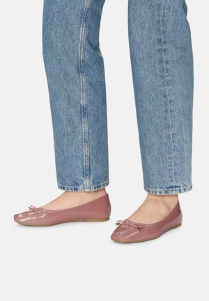Gładkie, różowe baletki z kokardką, płaską podeszwą i zaokrąglonym noskiem, zestawione z jasnoniebieskimi, podwiniętymi dżinsami. Gładka tekstura i minimalistyczny design.