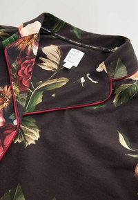 Tumedal lilledes print pajama top, millel on rohelised lehed, punased roosid ja kontrastne tumepunane äär kaeluses ja nuppudel.