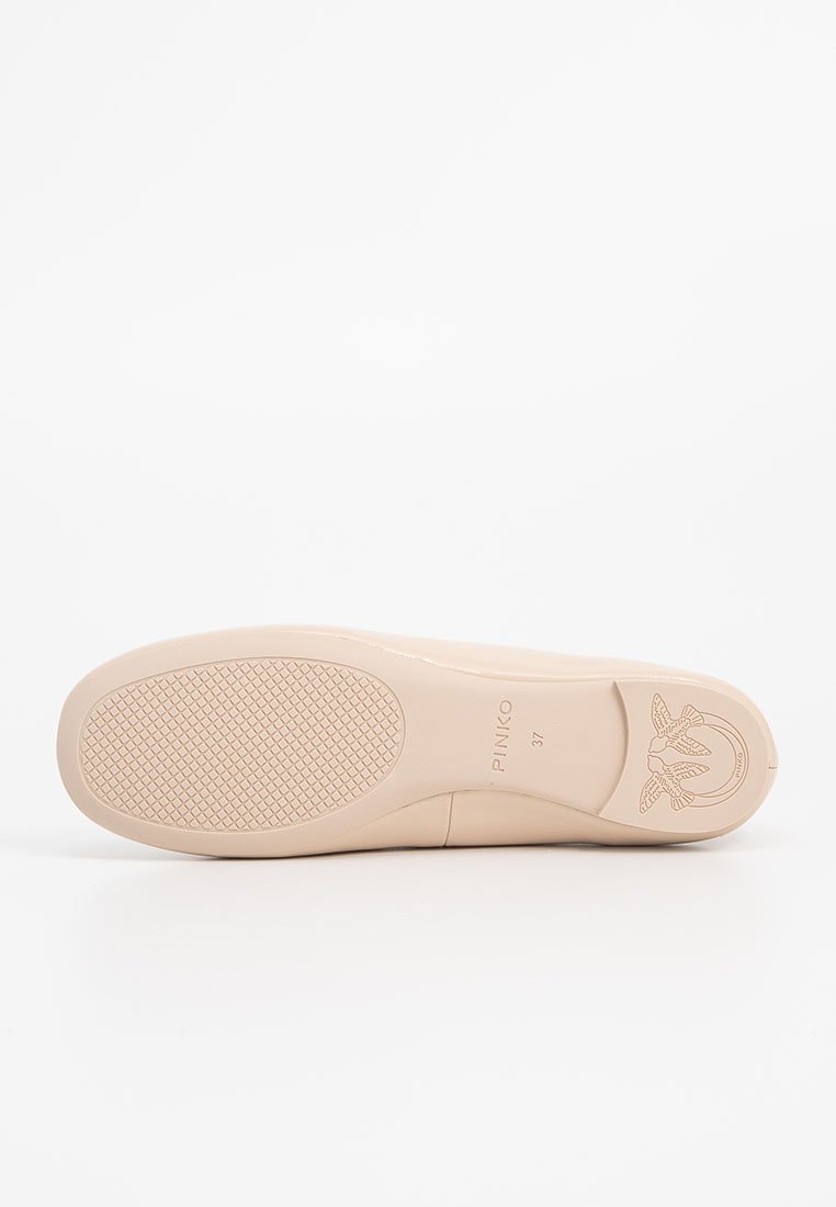 Zapato plano de color nude con un acabado suave y brillante. Presenta una suela de goma texturizada y un logo embosado en el tacón. Talla marcada como 37.