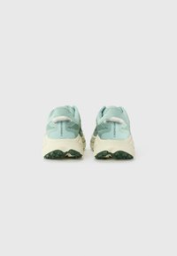 Hellgrüne Sportschuhe mit einer strukturierten Oberseite, gepolsterter Knöchelkante und beigefarbenem, kontrastierendem Schuhsohlenrand. Verfügt über eine strukturierte Gummisohle für besseren Halt.