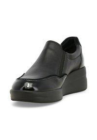 Scarpa nera in pelle scamosciata con finitura lucida, pannelli laterali elasticizzati e suola spessa. Presenta un design classico con cuciture a contrasto.
