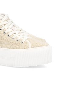 Zapatilla color crema con parte superior de tela texturizada, suela de goma blanca y cordones planos pasados por ojales plateados.