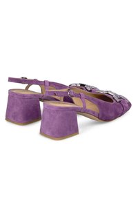 Scarpe con tacco alto in suede viola, dotate di tacco a blocco, con un design a incrocio e decorazioni decorative sulla parte anteriore. Cinghie alla caviglia regolabili.