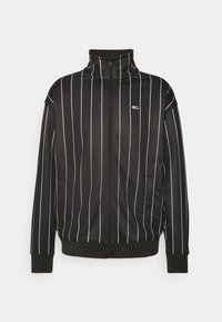 Svart zip-up jacka med vertikala vita ränder, hög krage och ribbade muddarn. Har sidofickor och en liten logga på vänster bröst.
