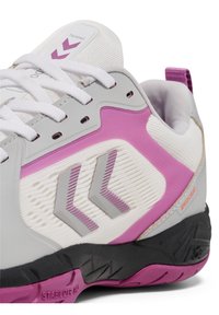 Scarpa sportiva grigia e bianca con accenti viola, caratterizzata da pannelli testurizzati, un tallone robusto e una suola nera con battistrada a motivo.