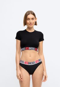 Μαύρο κοντό μπλουζάκι και ταυτόχρονο σετ μπικίνι με φαρδιά ζώνη που διαθέτει λευκή και κόκκινη επωνυμία "DIESEL". Λείο υφασμάτινο τελείωμα.