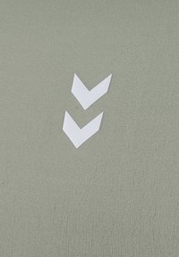 Topp i bomullsblandning i dov grön färg med två vita chevronformer som accenter. Mjuk textur med en figurnära design.