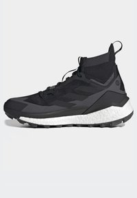Schwarzer Sportschuh mit einem strukturierten, gestrickten Obermaterial, ausgestattet mit einer weißen Zwischensohle und einer schwarzen Außensohle. Enthält Schnürsenkel und eine Zugschlaufe an der Ferse.