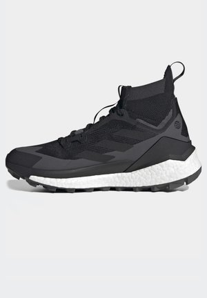 Black athletic shoe with a textured, knit upper, featuring a white midsole and black outsole. Includes laces and a pull tab at the heel.