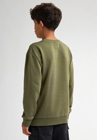Olijfgroen sweatshirt met lange mouwen, geribbelde ronde hals en manchetten. Zachte textuur, eenvoudig ontwerp en comfortabele pasvorm.