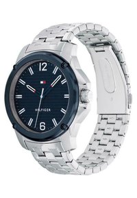 Montre en acier inoxydable argenté avec une lunette noire et un cadran texturé bleu, dotée d'index horaires blancs, d'un affichage de la date et d'un bracelet en chaîne maillée.