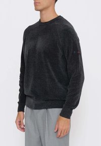 Maglione grigio scuro in tessuto morbido, con texture a coste sulle spalle, scollo rotondo e dettaglio con logo sulla manica.