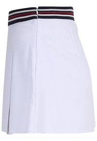 Weißer Skort mit einem elastischen Bund in Navy und Rot, weichem Stoff und seitlichem Schlitz für bessere Bewegungsfreiheit. Reißverschluss auf der Rückseite.