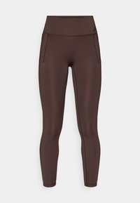 Leggings de sport marron avec une taille haute, une texture lisse, et des poches latérales discrètes. Présente un marquage subtil en noir près de la taille.