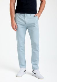 Svetlo modri chinos iz bombaža, s slim fit krojem, stranskimi žepi in gumbom za zapiranje. Oblečeni z belimi supergami.