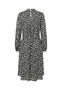 Robe à pois noir et blanc à manches longues avec une ceinture, ouverture en V dans le dos, et une jupe évasée. Fabriquée en tissu léger.