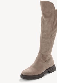 Beżowy zamszowy but do kolan z przeszyciem i matowym wykończeniem. Posiada okrągły czubek i teksturowaną gumową podeszwę dla lepszej przyczepności.