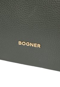 Ciemnozielona torba skórzana o strukturze, z wytłoczonym złotym logo "BOGNER" na powierzchni, prezentująca nowoczesny design.