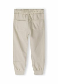 Beige katoenen joggingsbroek met een elastische tailleband, afgeronde enkels en twee achterzakken. Glad textuur met tonale stikdetails.