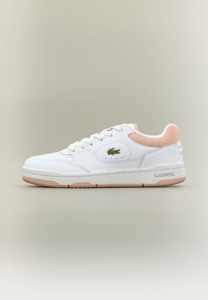 Baskets basses blanches avec accent rose au talon, design à lacets, semelle en caoutchouc et logo crocodile Lacoste vert sur le côté.