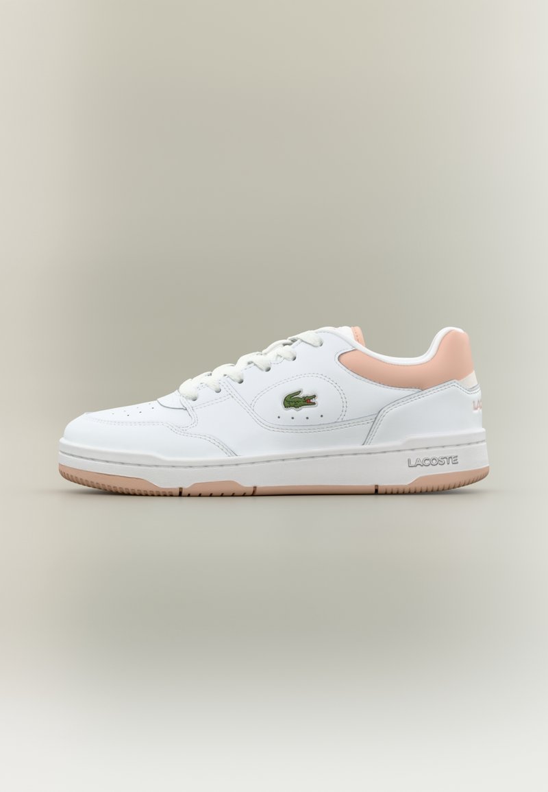 Baskets basses blanches avec accent rose au talon, design à lacets, semelle en caoutchouc et logo crocodile Lacoste vert sur le côté.