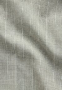 Tessuto intrecciato grigio chiaro con sottili righe verticali. La texture appare liscia e morbida, con una leggera lucentezza in alcune aree.