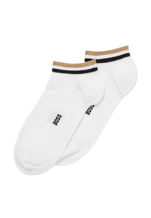 Calcetines blancos hasta el tobillo con un puño a rayas dorado y negro. Logotipo impreso en el lateral. Textura suave y diseño ajustado para mayor comodidad.