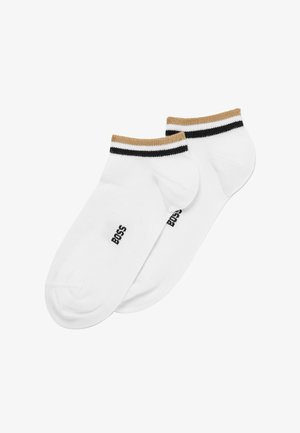 Calcetines blancos hasta el tobillo con un puño a rayas dorado y negro. Logotipo impreso en el lateral. Textura suave y diseño ajustado para mayor comodidad.