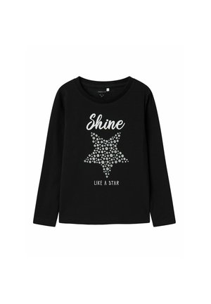 Camiseta negra de manga larga con una estrella plateada hecha de puntos, con el texto "Brilla como una estrella" debajo del gráfico. Material de algodón suave.