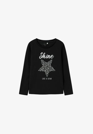 Camiseta negra de manga larga con una estrella plateada hecha de puntos, con el texto "Brilla como una estrella" debajo del gráfico. Material de algodón suave.