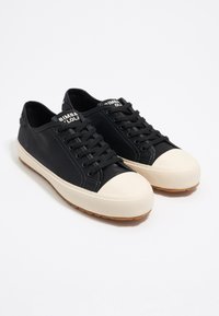 Sneaker nere con tomaia in pelle liscia, punta in gomma crema e suola in gomma marrone; presentano chiusura con lacci e logo sulla linguetta.