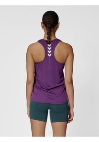 Fioletowy sportowy top bez rękawów z wycięciem na plecach i refleksyjnymi akcentami w kształcie zygzaka, w połączeniu z zielonymi szortami z teksturowanym pasem.