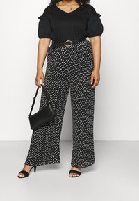 Černý top s výstřihem do V a nabíranými rukávy, v kombinaci s širokými kalhotami s potiskem bílých puntíků. Doplněno černým páskem a kabelkou.