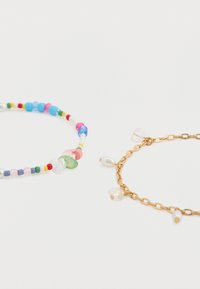 Δύο βραχιόλια: ένα πολύχρωμο βραχιόλι με χάντρες διαφόρων μικρών μεγεθών και ένα χρυσό βραχιόλι αλυσίδα με πέρλες και διαφανείς χάντρες.