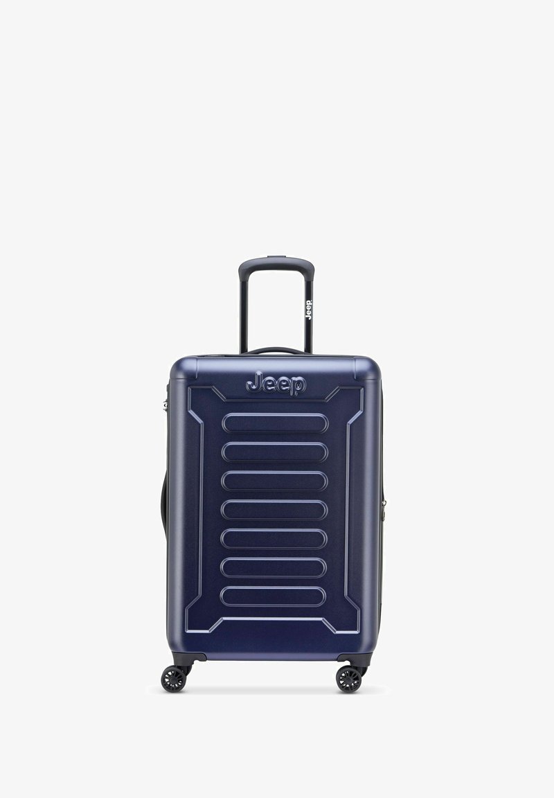 Valise rigide bleu marine avec texture rainurée, poignée rétractable et quatre roulettes. Présente le logo Jeep en haut.