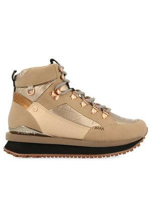 Sneaker beige mi-haut avec une finition en satin, des accents métalliques, des lacets ronds et une semelle en caoutchouc texturé avec un léger talon.