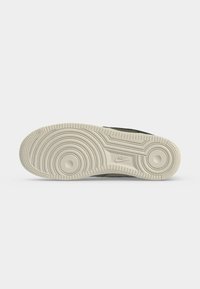 Σόλα αθλητικού παπουτσιού Nike που δείχνει κυκλικά σχέδια πέλματος και το λογότυπο της Nike στο κέντρο σε ανοιχτό γκρι φόντο.