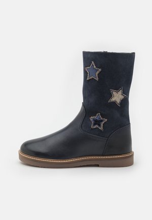 Schwarzer Stiefel bis zur Mitte der Wade mit brauner Sohle, der am Schaft drei sternförmige Patches aufweist, zwei dunkelblaue und einen mehrfarbig glitzernden Stern.