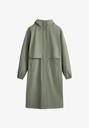Long manteau à capuche en tissu vert discret avec des poignets élastiques et deux poches latérales à fermeture éclair. Texture lisse avec un design minimaliste.