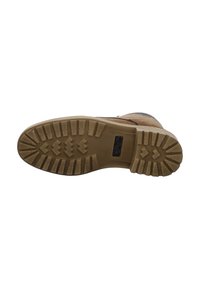 Semelle de botte en cuir marron avec un motif texturé rugueux, comportant des crampons profonds pour une meilleure traction et un logo intégré près du talon.
