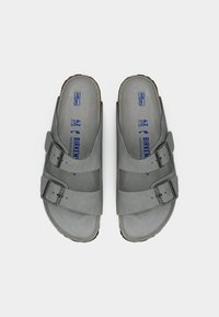 Γκρι σανδάλια από σουέτ με δύο ρυθμιζόμενες αγκράφες, καμπυλωτό πέλμα και επίπεδη λαστιχένια σόλα. Μέγεθος 42 σημειωμένο στο εσωτερικό.