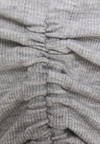 Tessuto grigio a coste con una texture arricciata. Materiale morbido e elastico con cuciture visibili e un motivo uniforme. Nessun dettaglio aggiuntivo presente.